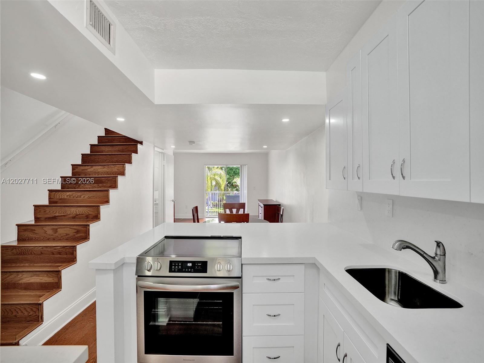 A modern kitchen with white cabinets and a stainless steel stove overlooks a dining area — 4600 SW 67th Ave # 255, Miami FL 33155, MIAMI, FL