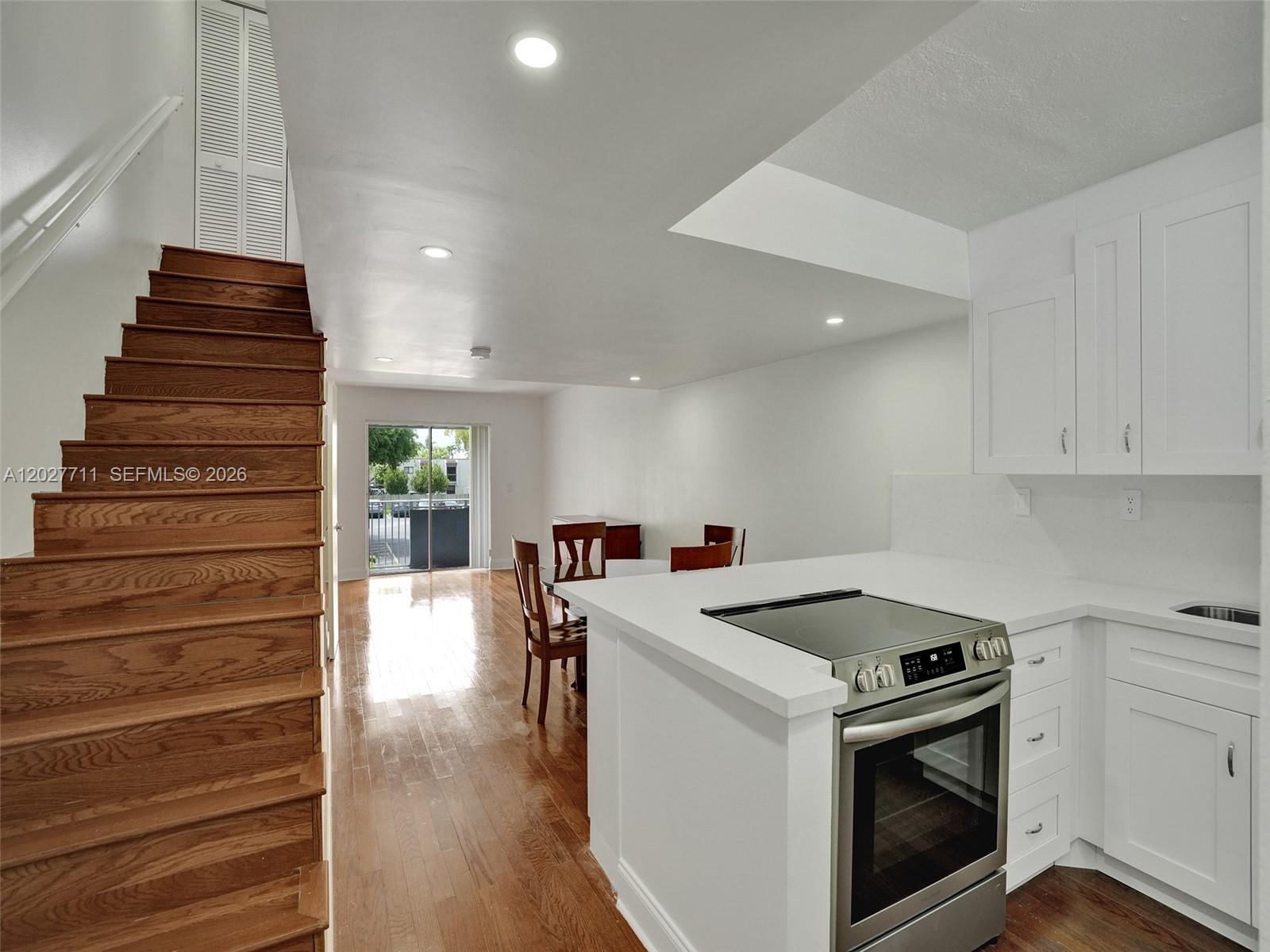 A kitchen with white cabinets and a stainless steel stove overlooks a dining area — 4600 SW 67th Ave # 255, Miami FL 33155, MIAMI, FL