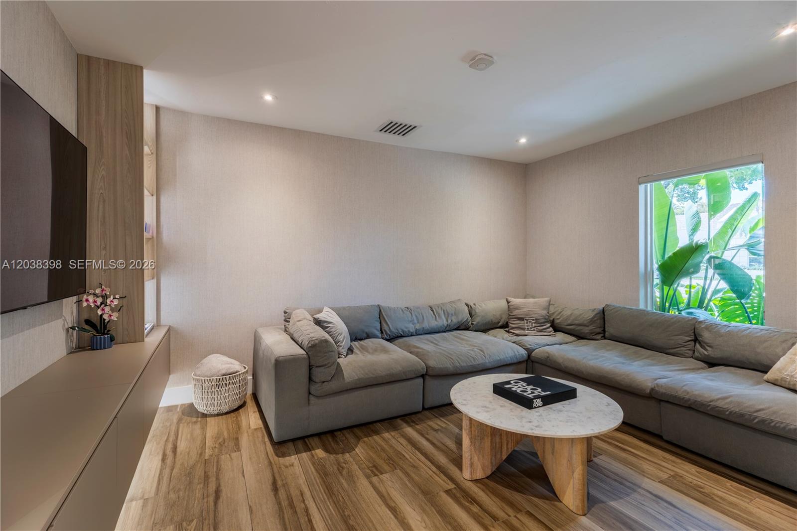 A living room features a large gray sectional sofa, a marble coffee table, and wood flooring — 2021 NE 212th St, Miami FL 33179, MIAMI, FL