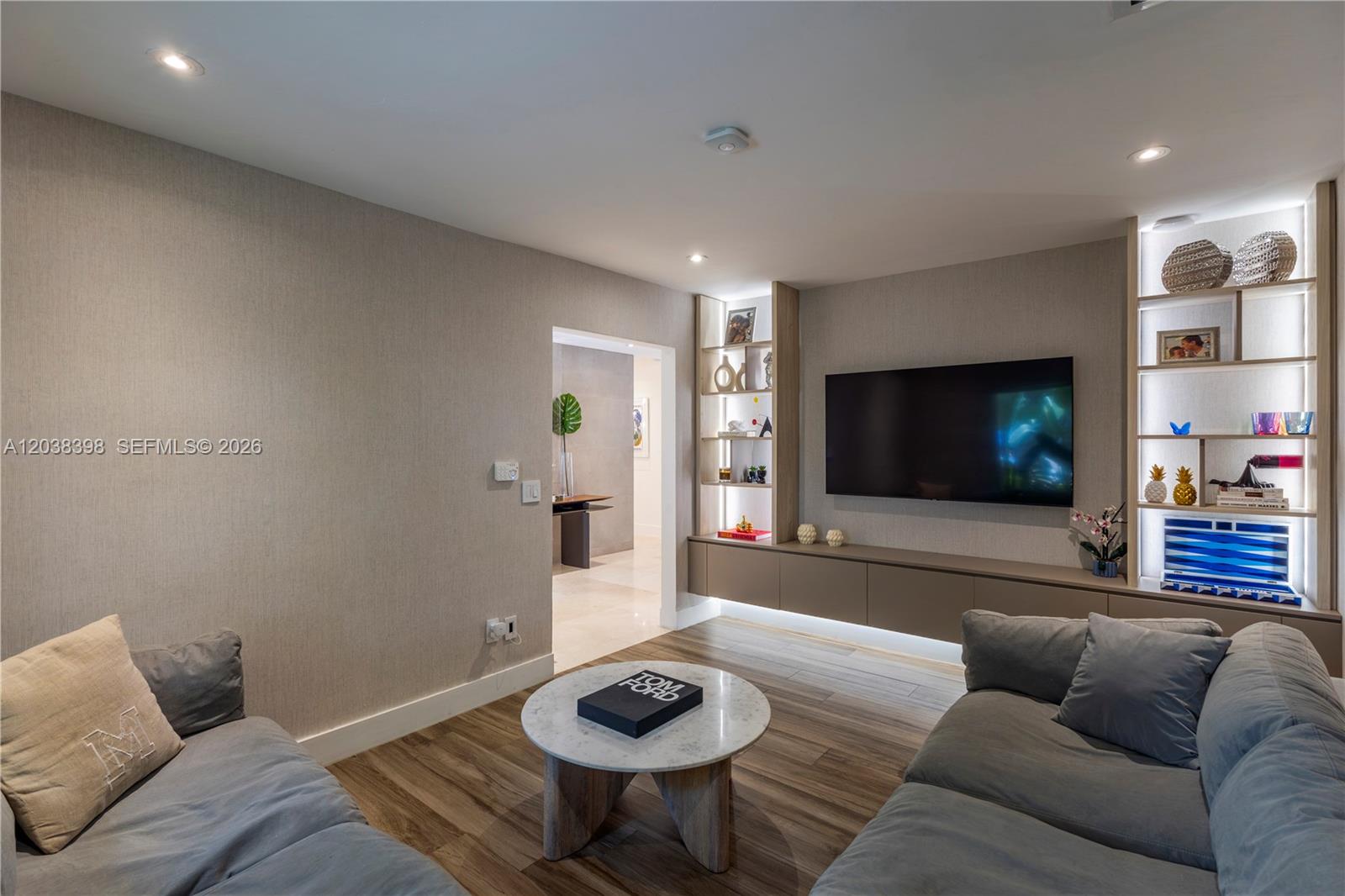 A living room features a wall-mounted television, built-in shelving, and two gray sofas — 2021 NE 212th St, Miami FL 33179, MIAMI, FL