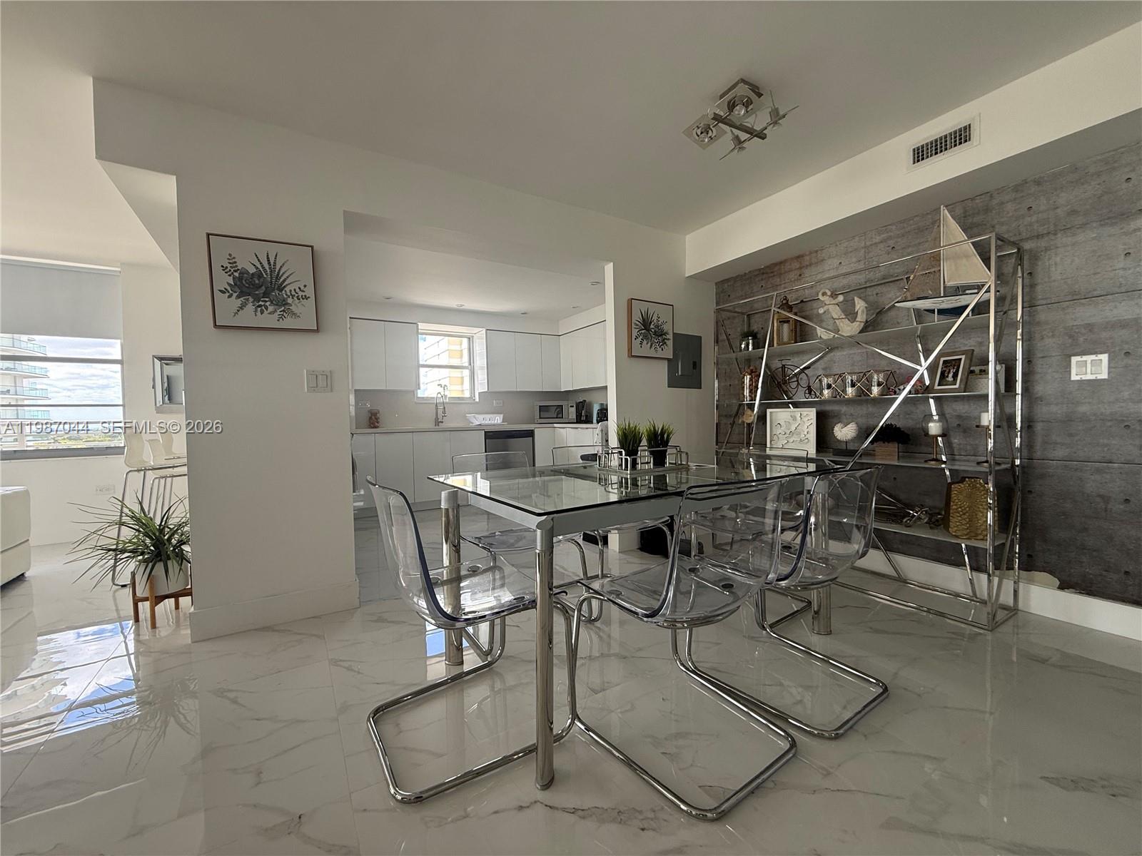 A dining area features a glass table, clear chairs, and a metal shelving unit — 5555 Collins Ave # 8R, Miami Beach FL 33140, MIAMI BEACH, FL