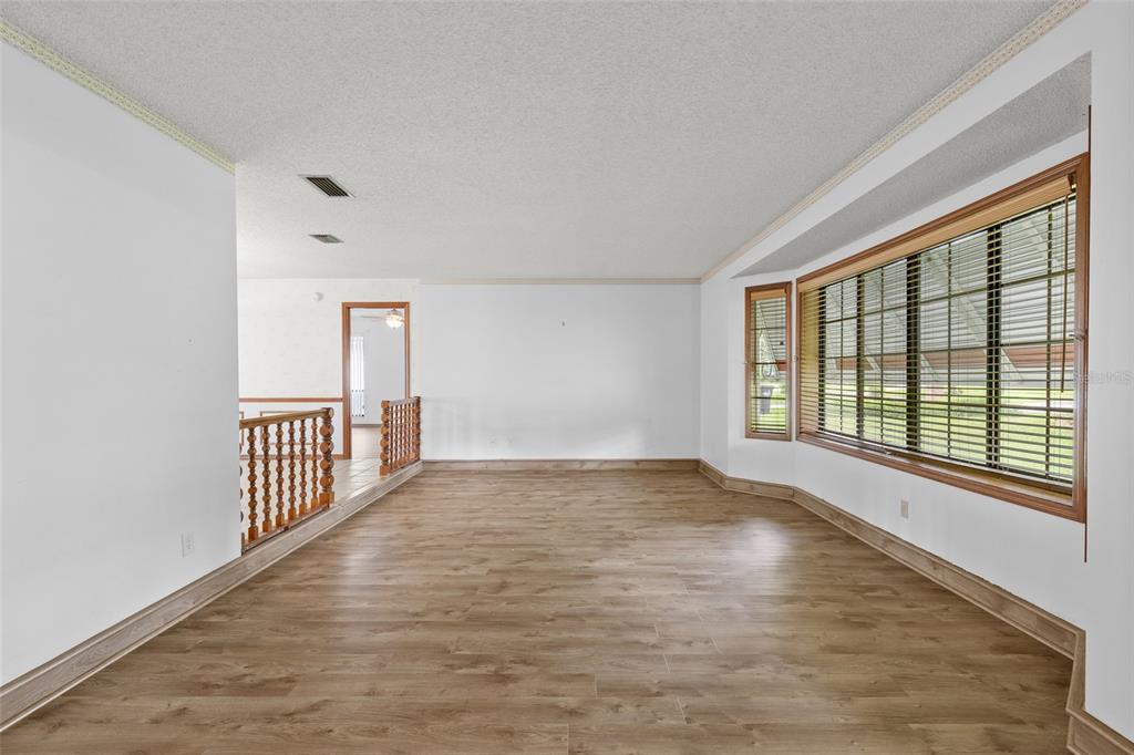 An empty room with wood-look flooring, white walls, and a large bay window with blinds — 521 FERNWOOD DRIVE, ALTAMONTE SPRINGS, FL