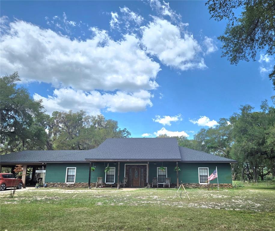 A green single-story house with a dark roof, stone foundation, and a front porch — 2672 SE 35TH STREET, SUMTERVILLE, FL
