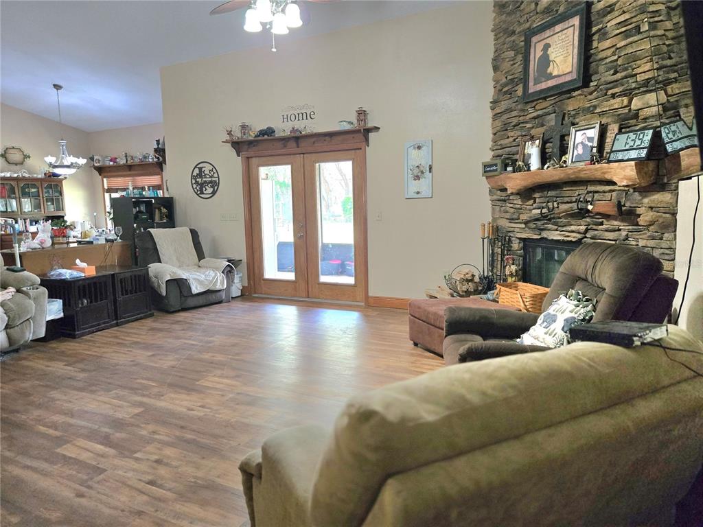 A living room features a stone fireplace, wood flooring, and double glass doors — 2672 SE 35TH STREET, SUMTERVILLE, FL