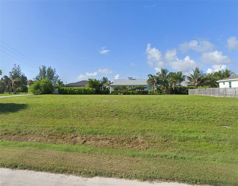 A vacant, grassy residential lot sits in front of a house and palm trees — 1715 PORPOISE AVENUE, FORT PIERCE, FL