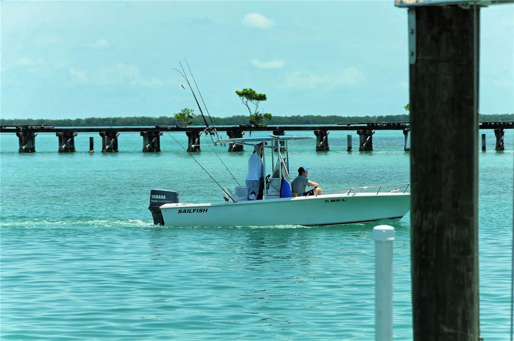 A white Sailfish motorboat with two people on board travels past a wooden bridge — 6040 BOCA GRANDE CAUSEWAY UNIT 5, BOCA GRANDE, FL