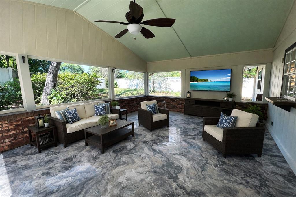 A screened-in patio features a vaulted ceiling, brick walls, and a marbled concrete floor — 700 SWARTHMORE ROAD, DELAND, FL