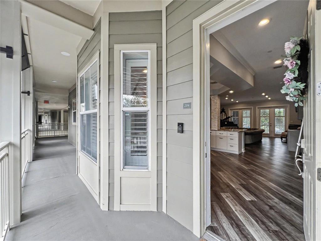 The view shows an apartment entryway with a balcony and an open-concept interior living space — 650 CAMPUS STREET UNIT 204, CELEBRATION, FL