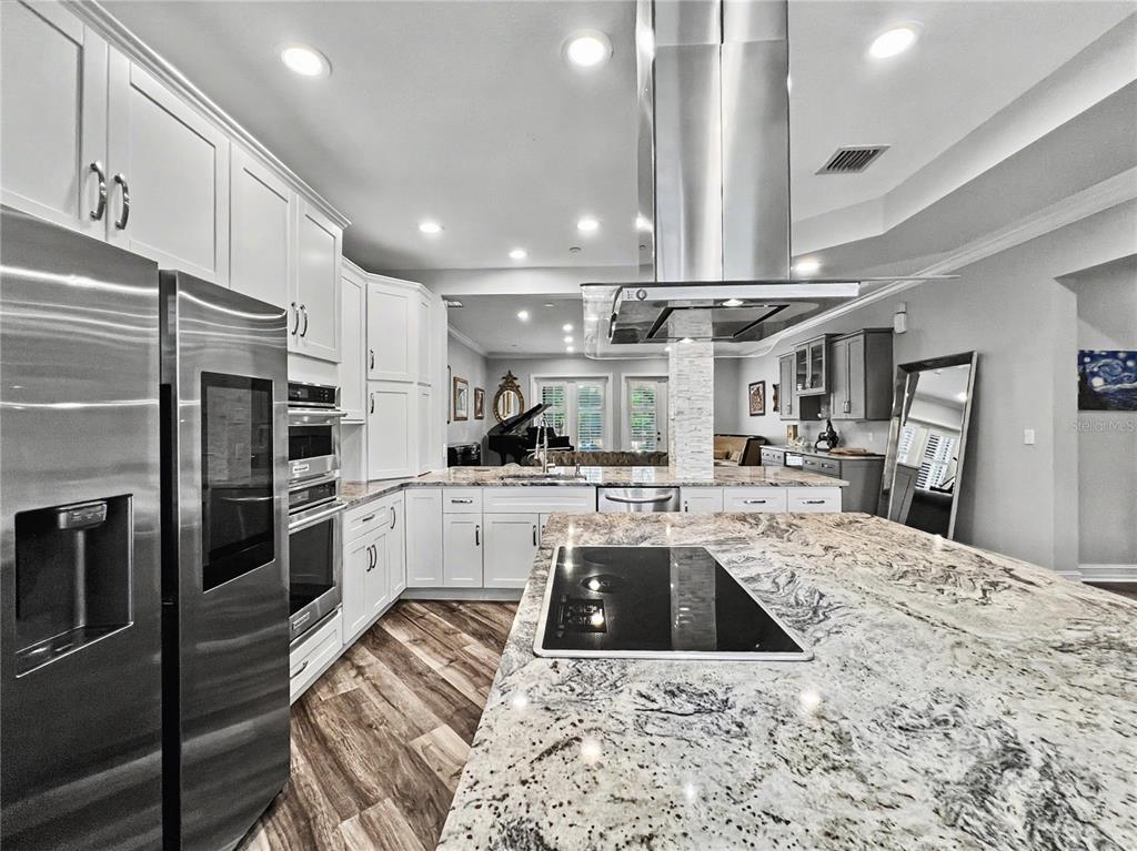 A modern kitchen features white cabinetry, granite countertops, a large island, and stainless steel appliances — 650 CAMPUS STREET UNIT 204, CELEBRATION, FL