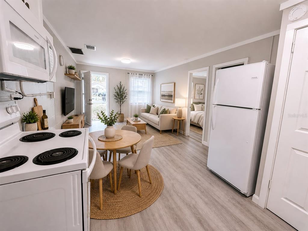 An open-concept living and dining area features light wood flooring, white walls, and a kitchen — 2305 SW 2ND STREET UNIT A, OCALA, FL
