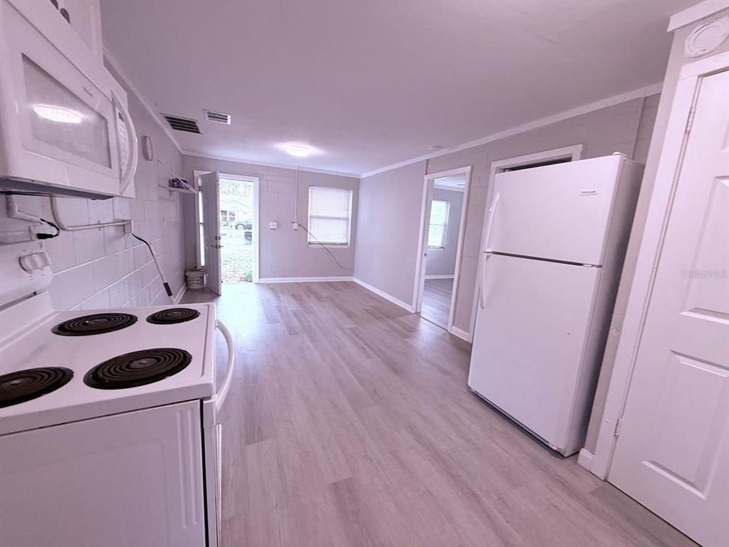 A kitchen with white appliances, light wood-look flooring, and painted concrete block walls — 2305 SW 2ND STREET UNIT A, OCALA, FL