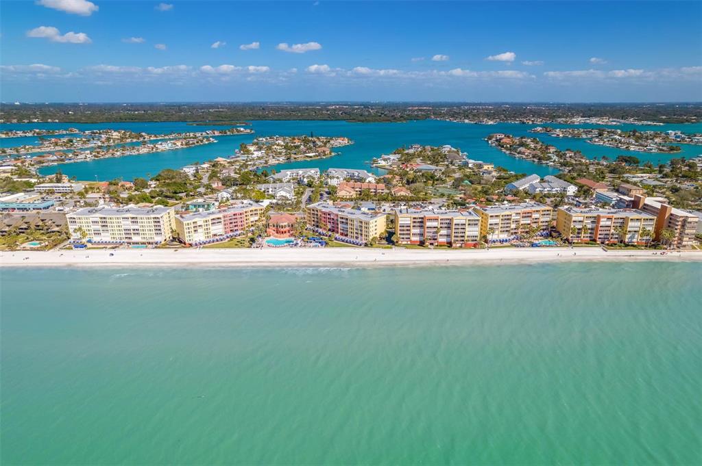 An aerial view of beachfront condominium buildings along a turquoise coastline with residential islands behind — 16550 GULF BOULEVARD UNIT 545, NORTH REDINGTON BEACH, FL