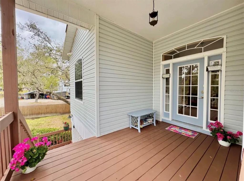 A wooden deck leads to a light blue front door with sidelights and a transom window — 1160 MILL CREEK, BRADENTON, FL