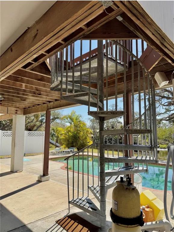 A metal spiral staircase leads to an elevated deck overlooking a backyard swimming pool — 1160 MILL CREEK, BRADENTON, FL