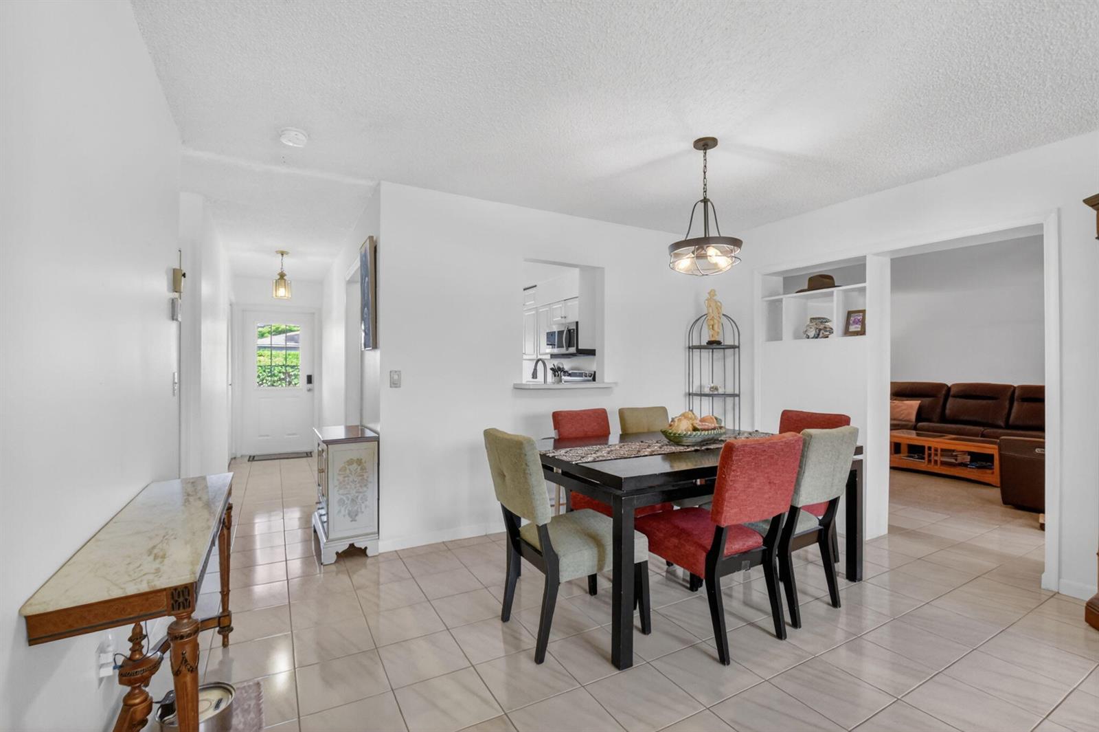A dining area with a dark table, colorful chairs, and tiled floors near an entryway — 14723 Wildflower Lane, Delray Beach FL 33446, DELRAY BEACH, FL