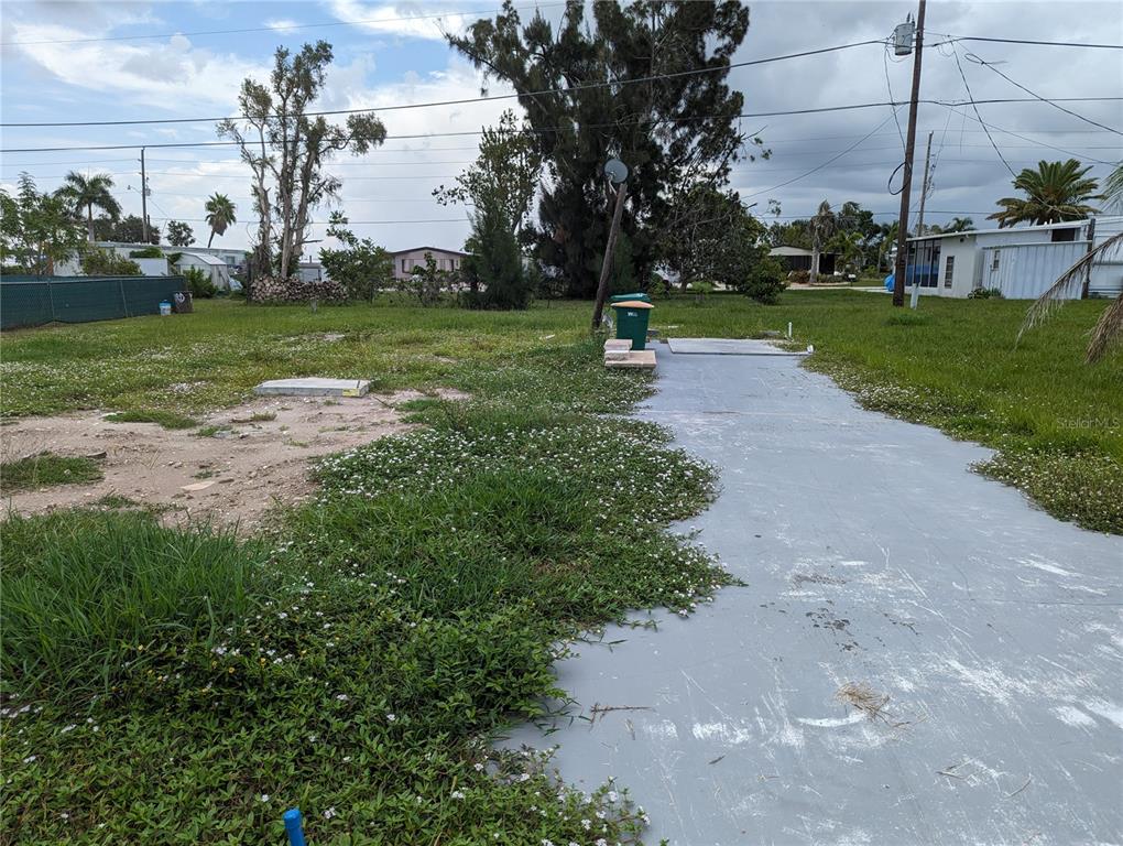 A vacant lot features a concrete driveway, a small slab, and a green trash bin — 1295 SEAGULL DRIVE, ENGLEWOOD, FL
