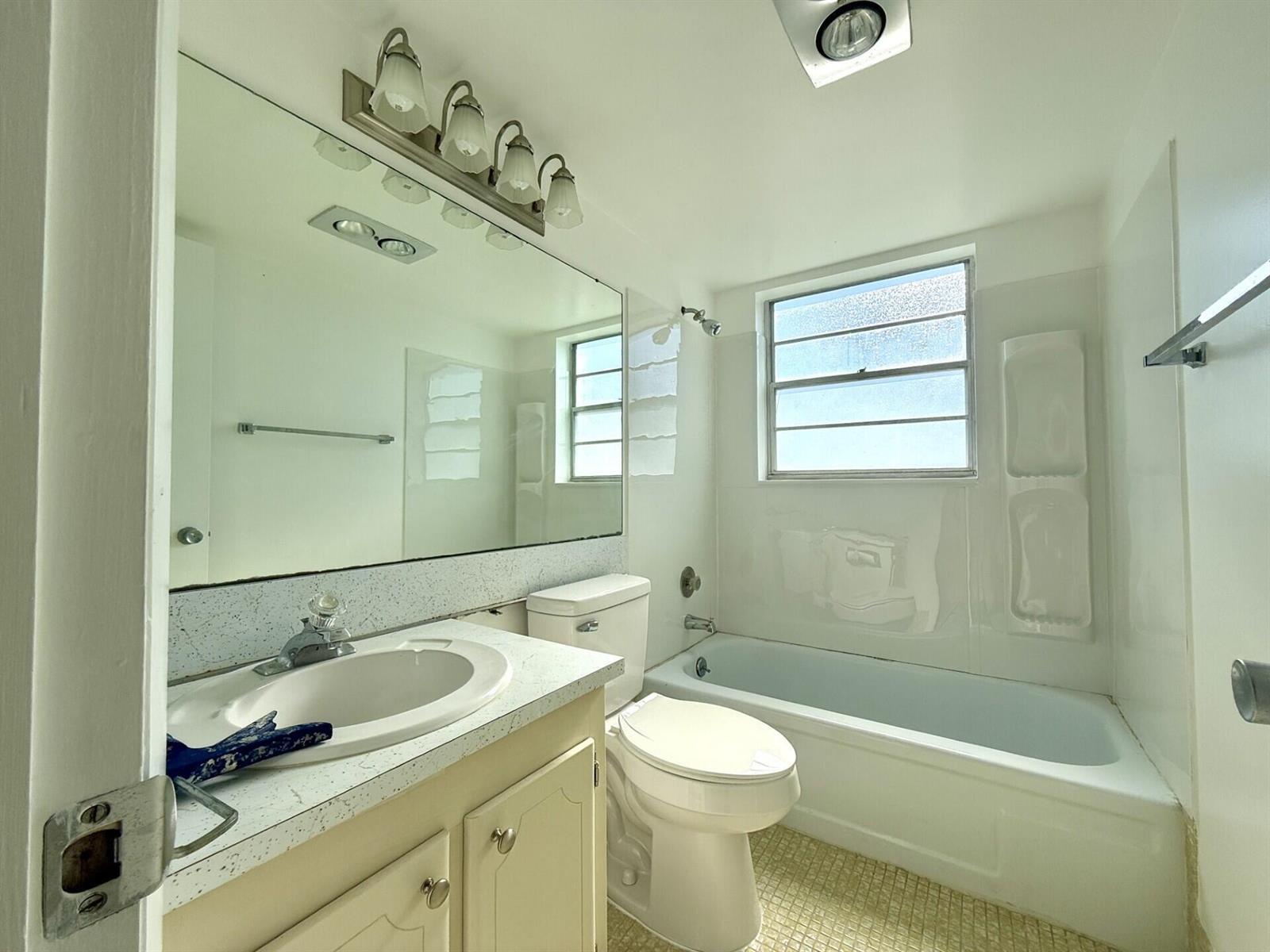 A bathroom features a white vanity, a toilet, and a bathtub with a shower surround — 9 Hastings A # 9, West Palm Beach FL 33417, WEST PALM BEACH, FL