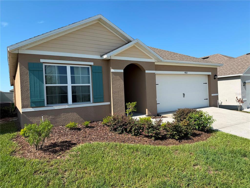 A single-story house with a tan stucco exterior, teal shutters, and a two-car garage — 4063 ALISSA LANE, HAINES CITY, FL