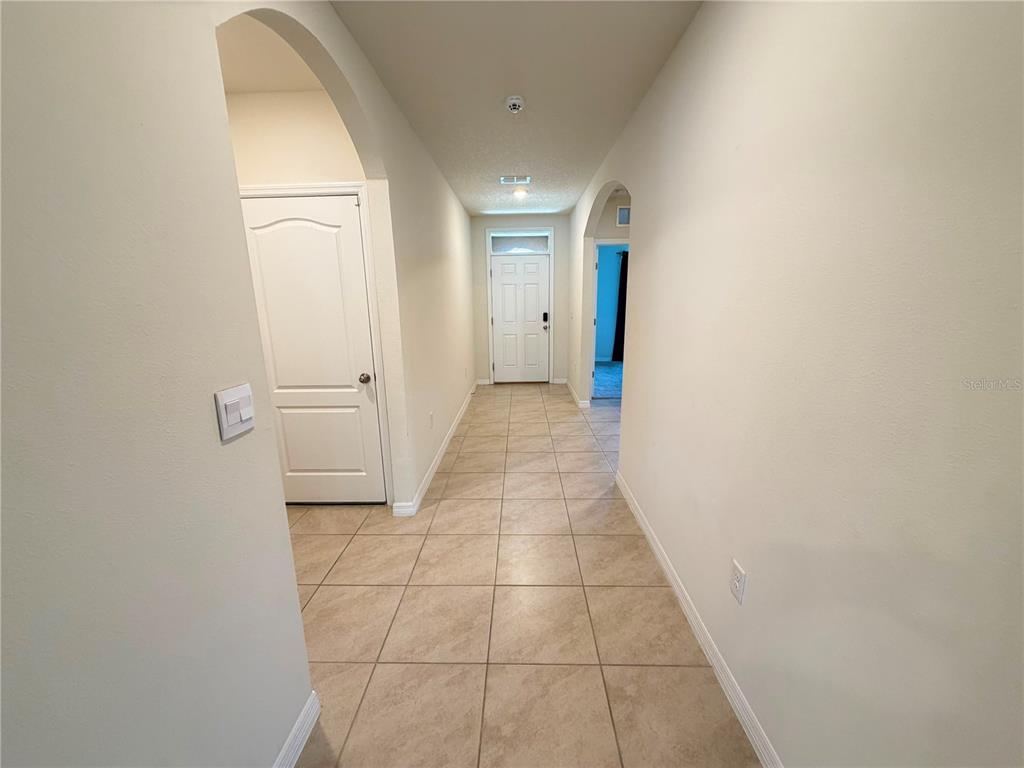 A tiled hallway leads to a front door with an arched entryway and white doors — 4063 ALISSA LANE, HAINES CITY, FL
