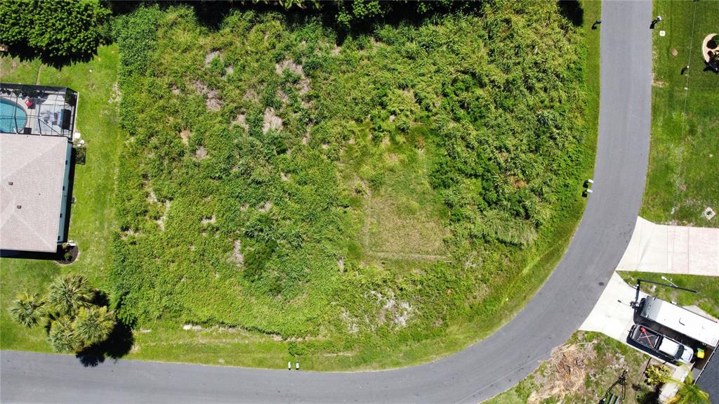An aerial view shows a vacant, overgrown residential lot situated between two existing houses — 18450 GOODMAN CIRCLE, PORT CHARLOTTE, FL
