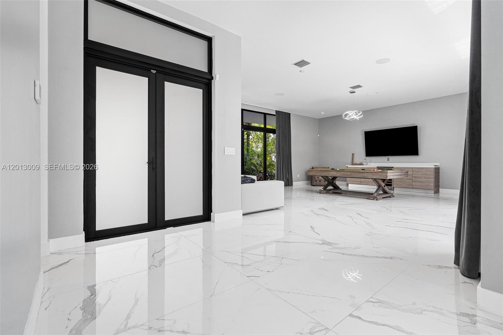 A spacious room features white marble floors, a pool table, and a wall-mounted television — 16529 N Botaniko Dr, Weston FL 33326, WESTON, FL