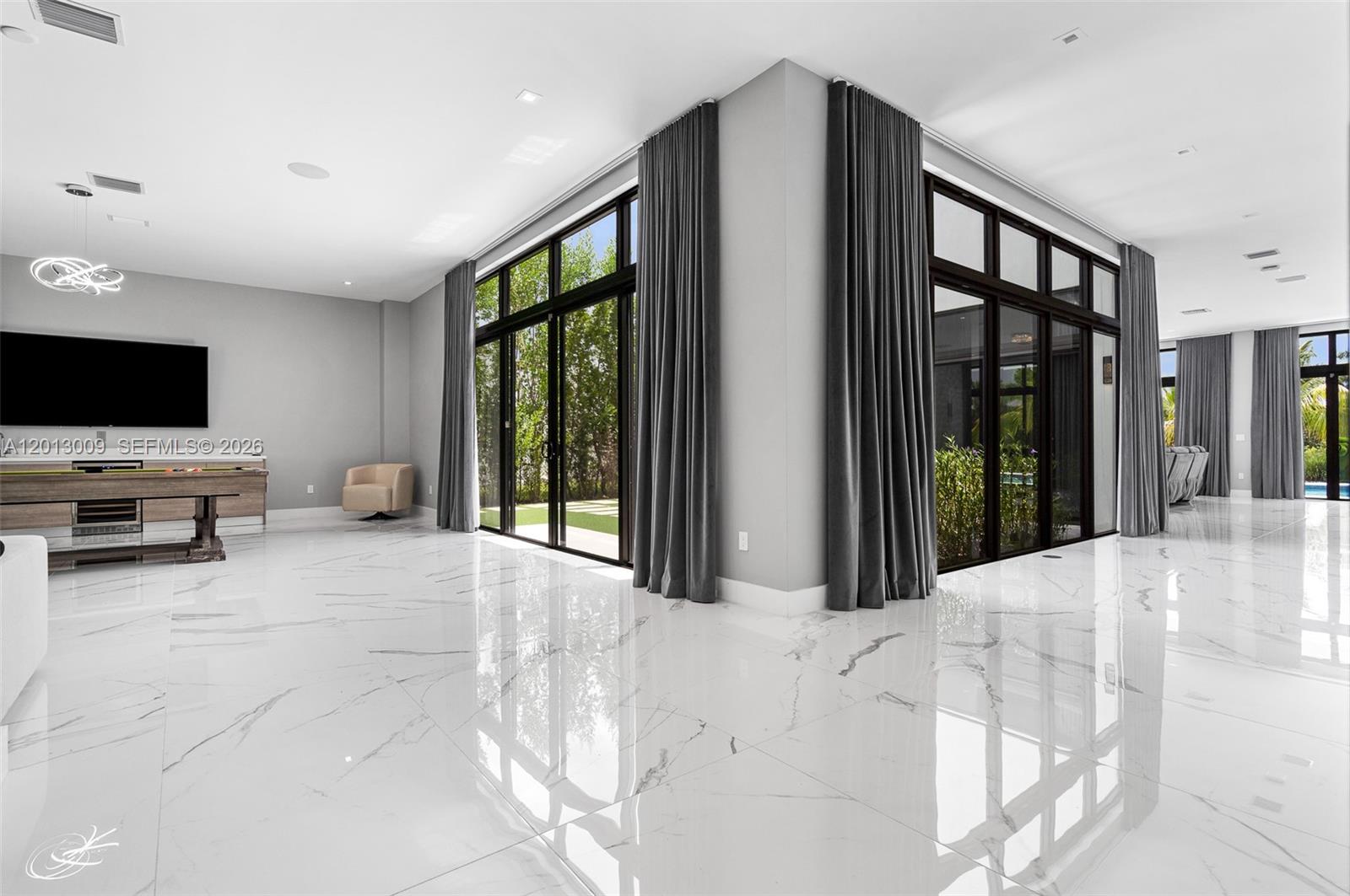 A modern living room features white marble floors, floor-to-ceiling windows, and dark gray curtains — 16529 N Botaniko Dr, Weston FL 33326, WESTON, FL