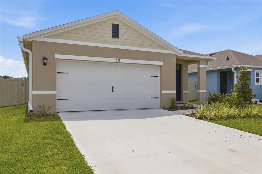 A tan, single-story house with a two-car garage and a concrete driveway — 3638 MARLBERRY WAY, SANFORD, FL