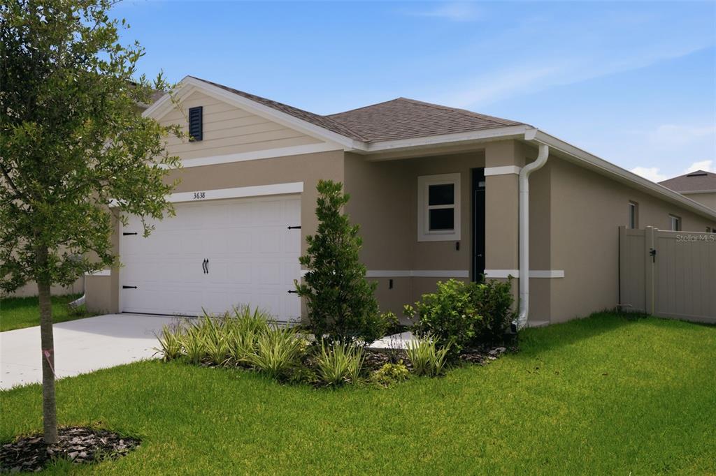 A single-story house with a tan stucco exterior, a white garage door, and a lawn — 3638 MARLBERRY WAY, SANFORD, FL