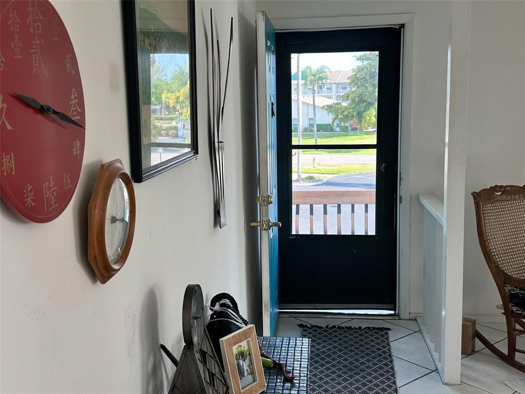 An entryway features a red wall clock, a wooden-framed mirror, and a door leading outside — 2829 74TH STREET W UNIT 2829, BRADENTON, FL