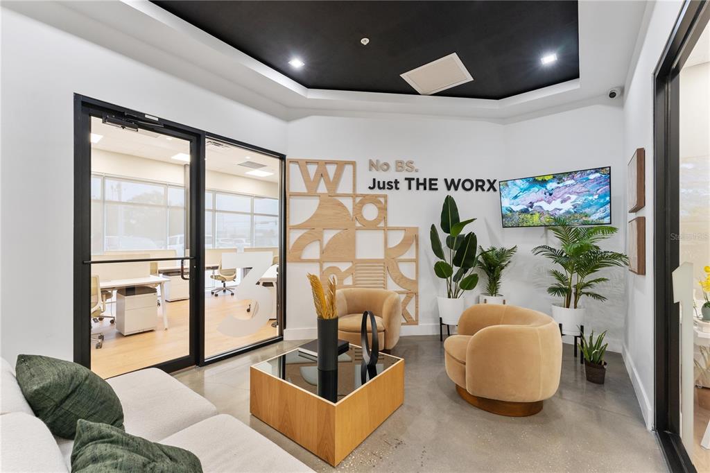 A modern office waiting area features a seating group, decorative wall art, and glass doors — 7726 WINEGARD ROAD, ORLANDO, FL