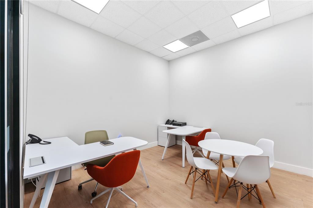 An office space features white desks, modern chairs, light wood flooring, and recessed ceiling lights — 7726 WINEGARD ROAD, ORLANDO, FL