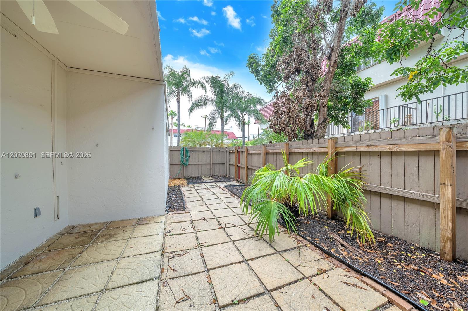 A paved patio area features a small palm plant and a wooden privacy fence — 8650 SW 67th Ave # 1010, Pinecrest FL 33156, PINECREST, FL