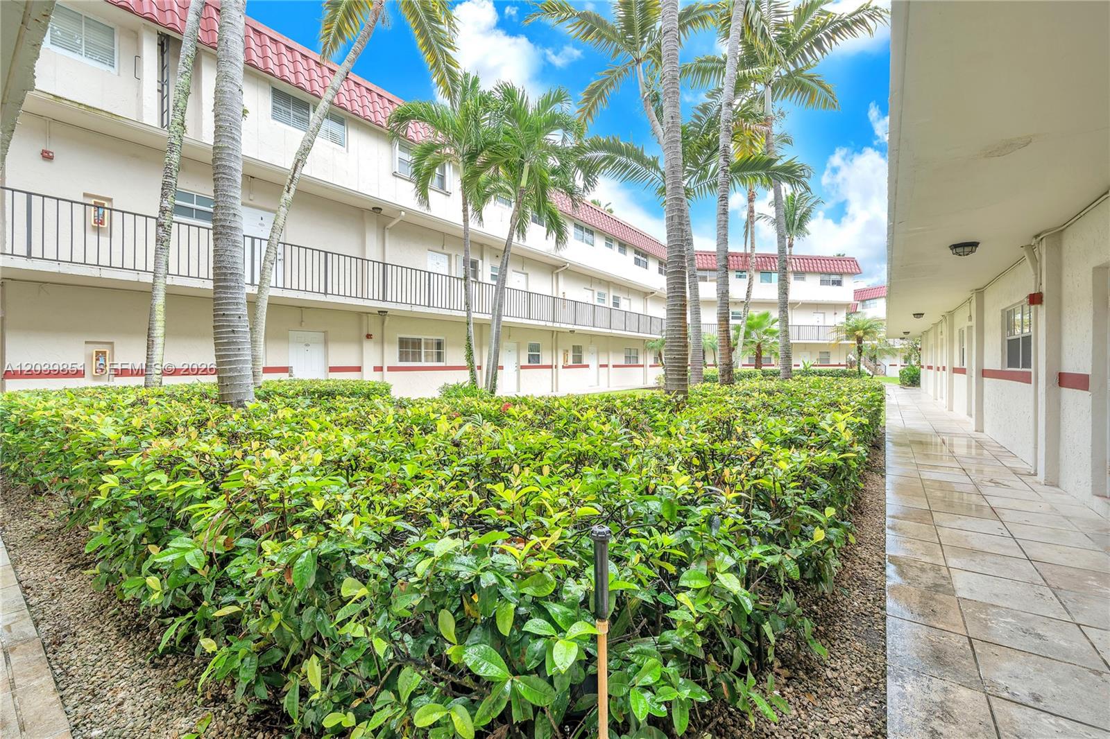 An exterior view shows a multi-story apartment building with a walkway, palm trees, and landscaping — 8650 SW 67th Ave # 1010, Pinecrest FL 33156, PINECREST, FL