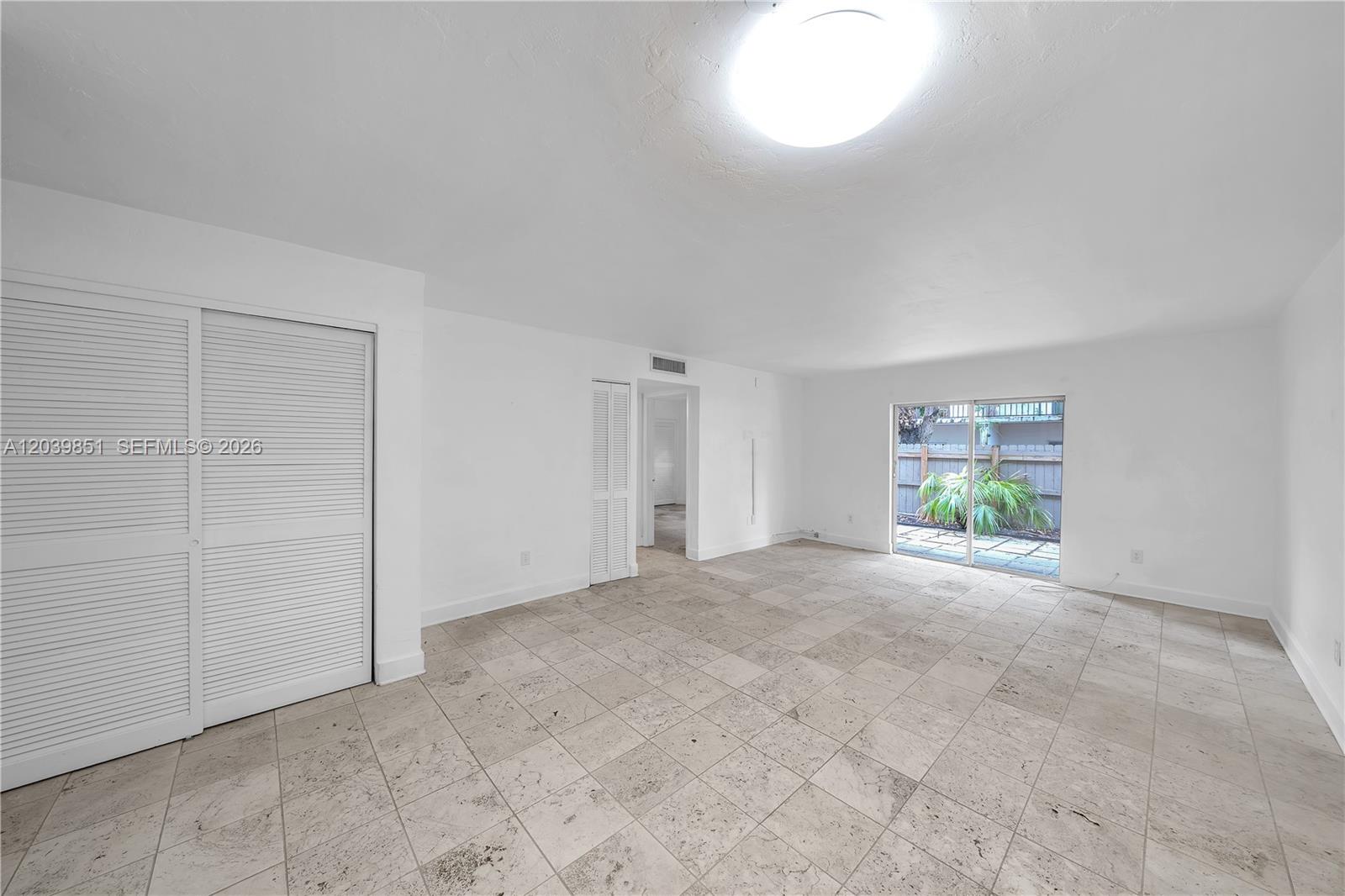 An empty room features white walls, tiled flooring, a large closet, and a sliding glass door — 8650 SW 67th Ave # 1010, Pinecrest FL 33156, PINECREST, FL