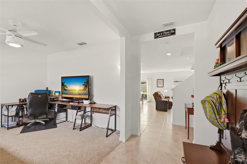 A home office with a desk and computer sits beside a tiled hallway leading indoors — 33428 COUNTRY HOUSE DRIVE, SORRENTO, FL