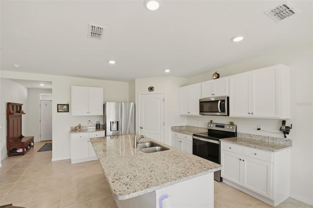 A kitchen features white cabinets, granite countertops, a central island, and stainless steel appliances — 33428 COUNTRY HOUSE DRIVE, SORRENTO, FL