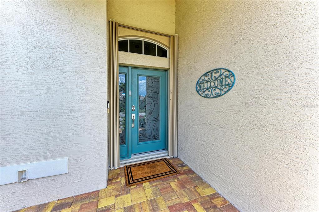 A teal front door with glass inserts sits under an arched transom on a porch — 1920 COCONUT PALM CIRCLE, NORTH PORT, FL