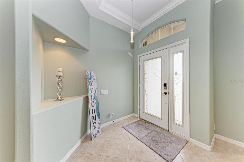 An entryway features light green walls, tile flooring, a recessed niche, and a glass-paneled door — 1920 COCONUT PALM CIRCLE, NORTH PORT, FL