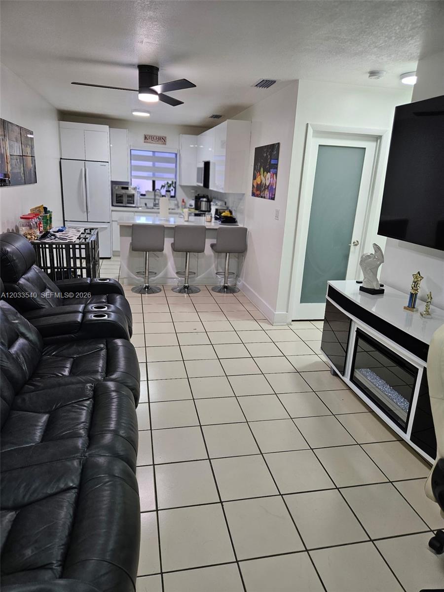 A living room with tile floors leads into an open kitchen with a breakfast bar — 2348 W 56th St # 19, Hialeah FL 33016, HIALEAH, FL