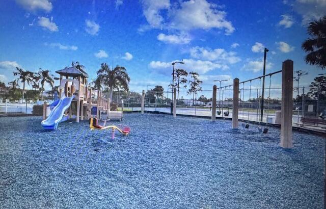 A playground features a slide, a seesaw, and a swing set on a wood-chipped surface — 503 Landings Boulevard, FL 33413, FL