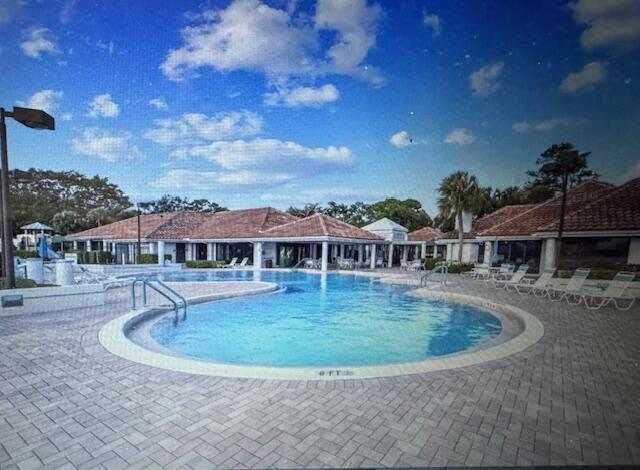 A swimming pool with a paved deck sits in front of a building with tiled roofs — 503 Landings Boulevard, FL 33413, FL