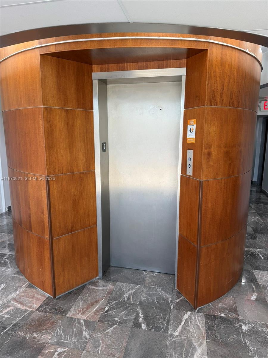 An elevator with wood-paneled walls and a marble floor in a building hallway — 2650 SW 27th Ave, Miami FL 33133, MIAMI, FL