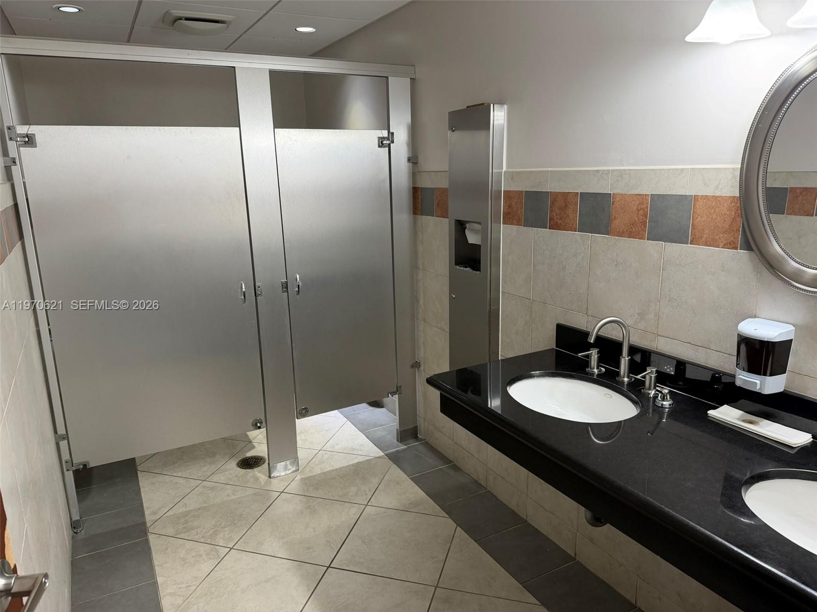 A commercial restroom features two metal stalls, a black granite vanity, and tiled walls — 2650 SW 27th Ave, Miami FL 33133, MIAMI, FL