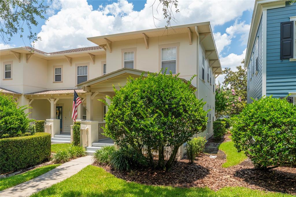 A two-story beige house with a front porch, American flag, and surrounding landscaping — 1037 OLD BLUSH RD, CELEBRATION, FL