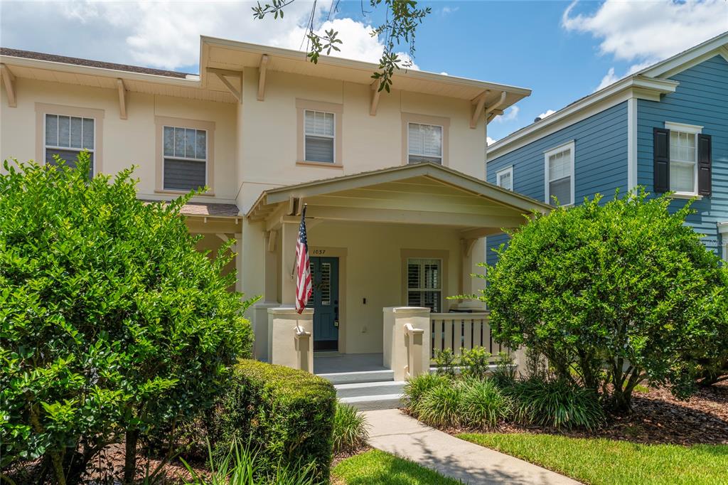 A two-story house with a beige stucco exterior, a front porch, and a blue door — 1037 OLD BLUSH RD, CELEBRATION, FL