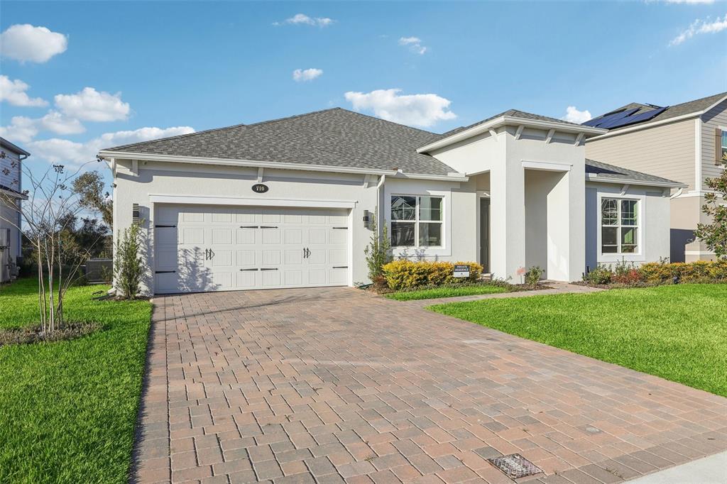 A single-story house with a paved driveway, white garage, and light-colored stucco exterior — 710 CREEPING FIG STREET, APOPKA, FL