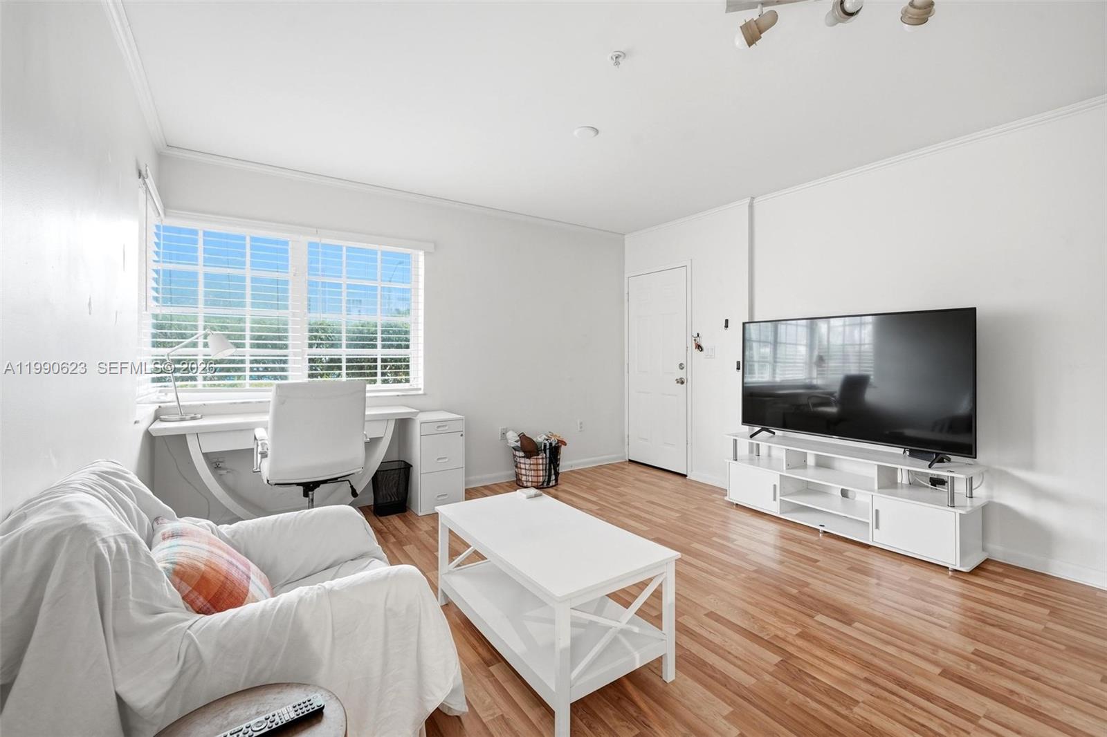 A living room features white walls, wood-look flooring, a desk, a sofa, and a television — 600 Euclid Ave # A2, Miami Beach FL 33139, MIAMI BEACH, FL