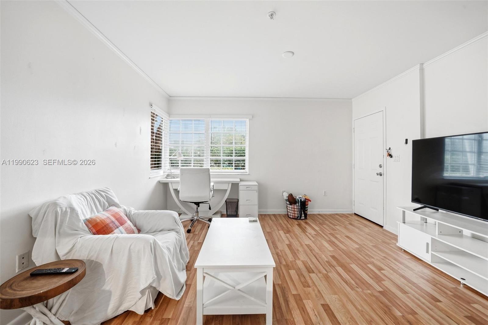 A living room features white walls, wood-look flooring, a desk, and a television — 600 Euclid Ave # A2, Miami Beach FL 33139, MIAMI BEACH, FL