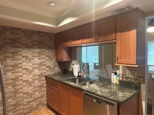 A kitchen features wood cabinets, granite countertops, a stainless steel dishwasher, and a stone-tiled wall — 7102 W COUNTRY CLUB DRIVE N, SARASOTA, FL