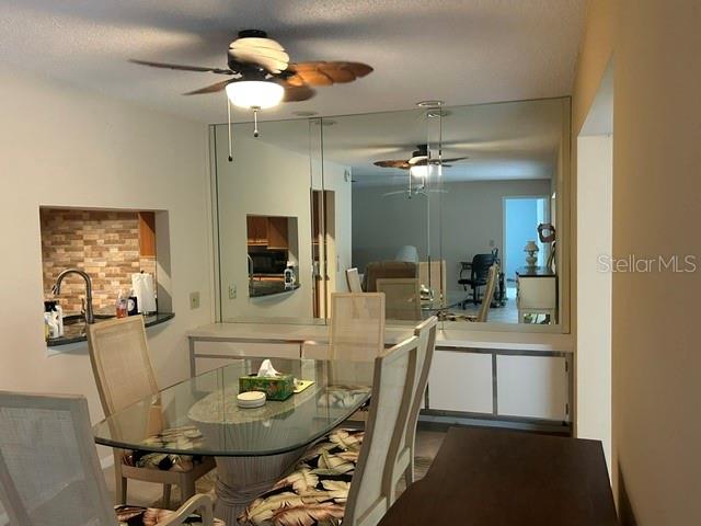 A dining area features a glass table, chairs, a ceiling fan, and a mirrored wall — 7102 W COUNTRY CLUB DRIVE N, SARASOTA, FL